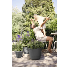 Vader en dochter spelen in de tuin naast plantenbakken op een houten terras