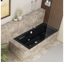 Moderne badkamer met zwart bad, marmeren bekleding en douchewand.