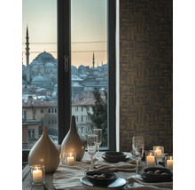 Decoratieve eettafel met servies, glazen, kaarsen en vazen voor een raam met uitzicht op de stad.