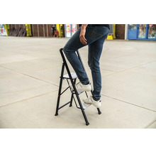 Persoon op een opklapbare trap met twee treden.