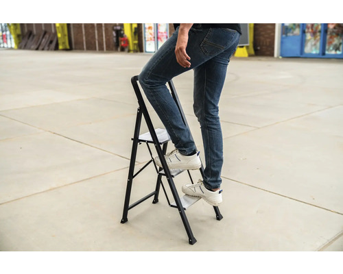 Persoon op een opklapbare trap met twee treden.