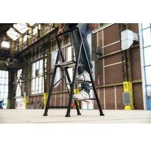 Een persoon staat op een huishoudtrap met drie treden.