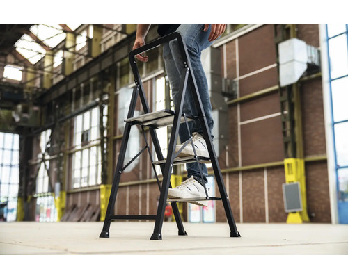 Een persoon staat op een huishoudtrap met drie treden.