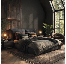 Slaapkamer met bed, nachtkastjes, lampen, vloerkleed en fauteuil in donkere kleuren