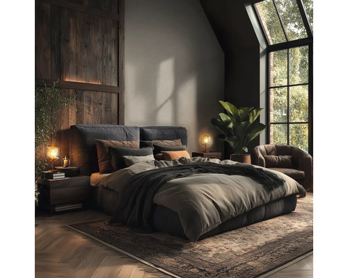 Slaapkamer met tweepersoonsbed, nachtkastjes, lampen, fauteuil, kamerplant en vloerkleed.