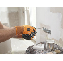 Een persoon bevestigt met een schroevendraaier een beugel aan een muur. Op een tafel staan een spons, een blik en een penseel.