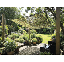 Tuin met camouflage net als zonwering boven een zithoek
