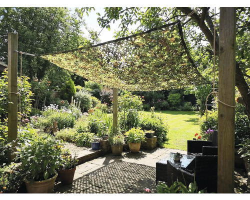 Tuin met camouflage net als zonwering boven een zithoek
