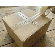 Een kartonnen doos wordt afgesloten met transparante tape.