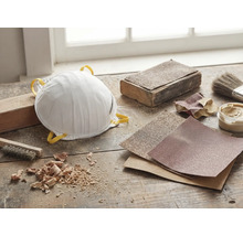 Stofmasker, schuurpapier en gereedschap op een werkbank