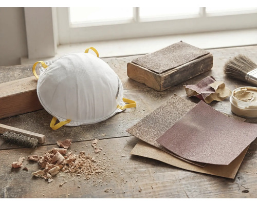 Stofmasker, schuurpapier en gereedschap op een werkbank