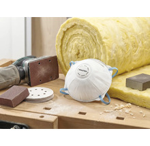 Scène met stofmasker, schuurpapier, schuurmachine en isolatiewol op een werkbank.