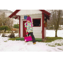 Meisje schept sneeuw voor een speelhuis in de tuin
