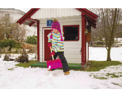 Meisje schept sneeuw voor een speelhuis in de tuin