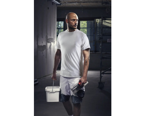Vakman met T-shirt, korte broek, emmer en troffel op een bouwplaats