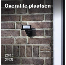 Batterijgevoede lamp met bewegingsmelder gemonteerd op een bakstenen muur