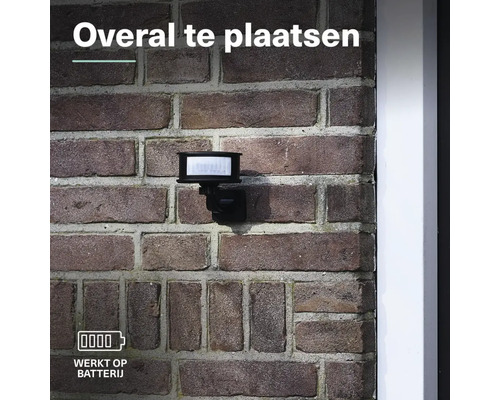 Batterijgevoede lamp met bewegingsmelder gemonteerd op een bakstenen muur