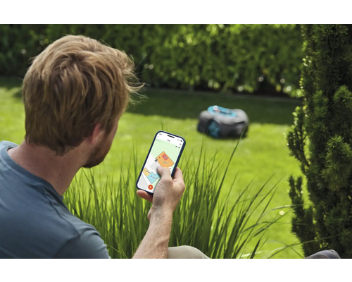 Man bedient gazonmaaierrobot via smartphone in de tuin