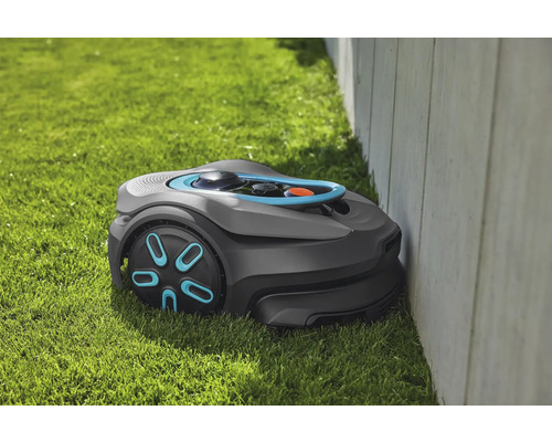 Robotmaaier op gazon naast een muur