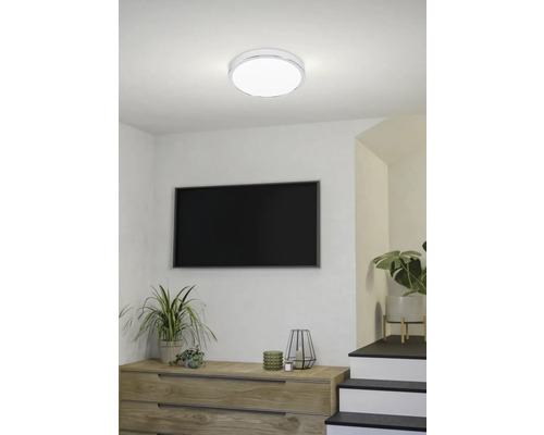 Moderne woonkamer met LED-plafondlamp, dressoir, televisie en kamerplanten.