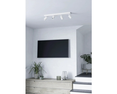 Woonkamer met plafondlamp met vier spots, televisie en dressoir