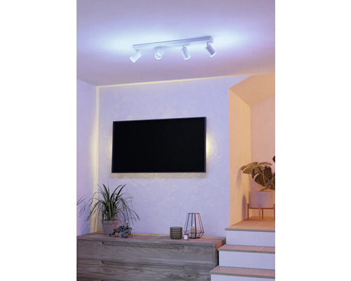 Woonkamer met flatscreen televisie, dressoir, kamerplanten en plafondlamp met meerdere spots