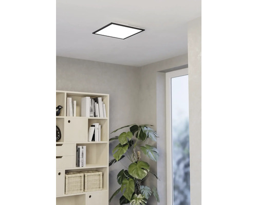 Vierkante plafondlamp in een lichte kamer met boekenkast en kamerplant
