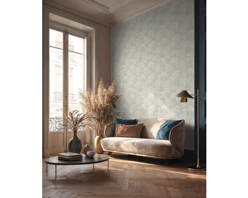 Woonkamer met bank, salontafel, vloerlamp en behang met boommotief