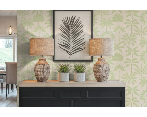 Decoratieve scène met twee lampen, planten en een ingelijste foto op een dressoir voor een behang met palmmotief