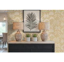 Decoratief interieur met twee lampen, twee kamerplanten, een ingelijste afbeelding en een dressoir tegen een muur met palmmotief.