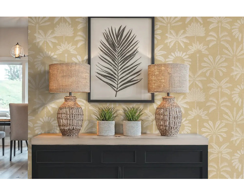 Decoratief interieur met twee lampen, twee kamerplanten, een ingelijste afbeelding en een dressoir tegen een muur met palmmotief.