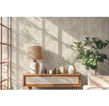 Woonkamer met botanisch behang, lamp, decoratie en plant op een houten kast.