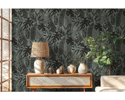 Decoratieve kamer met een behang met een tropisch plantenmotief, een lamp en planten op een houten meubel.