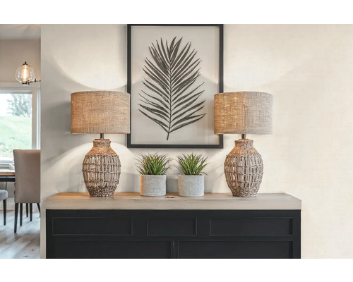 Decoratieve scène met twee tafellampen, twee potplanten en een ingelijste bladprint op een kast