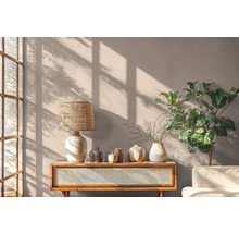 Woonkamer met houten tafel, lamp, vazen en plant voor een muur