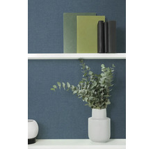 Decoratieve boeken en eucalyptus in een vaas op een plank.