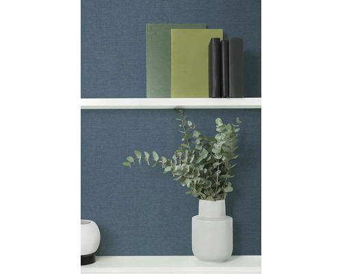 Decoratieve boeken en eucalyptus in een vaas op een plank.