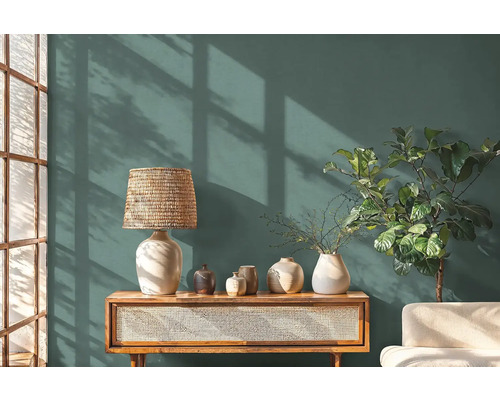 Woonkamer met een dressoir, een lamp, vazen en een kamerplant voor een muur