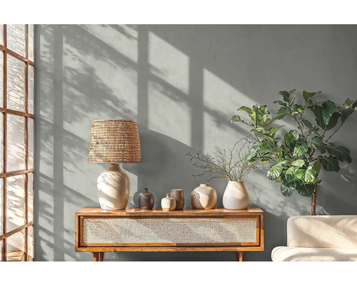 Woonkamer met tafellamp, decoratie en plant op een houten kast.