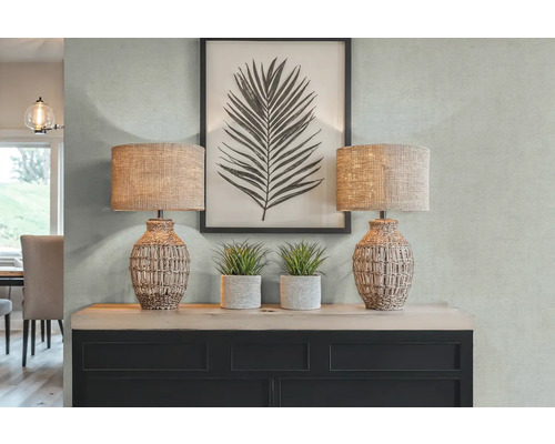 Decoratief interieur met twee tafellampen, kunstplanten en een ingelijste bladprint op een dressoir.