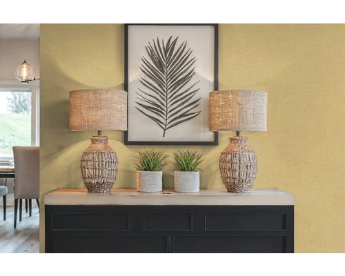 Decoratief interieur met twee tafellampen, planten en een ingelijste bladprint op een dressoir