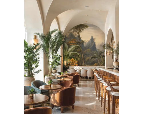 Heldere barruimte met booggewelven, tropische muurschildering, houten meubels, fluwelen fauteuils en grote kamerpalmen.