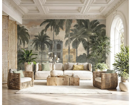 Fotobehang met palmbomen en koloniale gebouwen in een lichte woonkamer met witte bank, rotan fauteuils en houten salontafel.