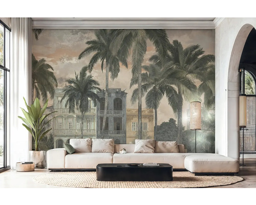 Lichte woonkamer met fotobehang in vintage stijl met palmbomen en koloniale gebouwen. Witte hoekbank, zwarte salontafel en gevlochten kleed.