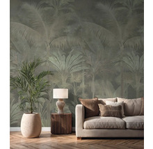 Vliesbehang met palmenpatroon in een lichte woonkamer achter een crèmekleurige bank, een tafellamp en een grote kamerplant.