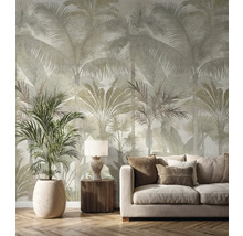 Vliesbehang met groot palmenpatroon in een lichte woonkamer met beige bank, houten meubels en een grote kamerplant.