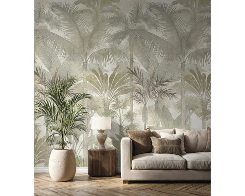 Vliesbehang met groot palmenpatroon in een lichte woonkamer met beige bank, houten meubels en een grote kamerplant.