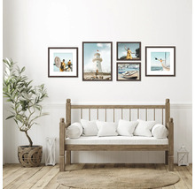 Decoratieve fotolijsten met kustmotieven boven een bank met kussens