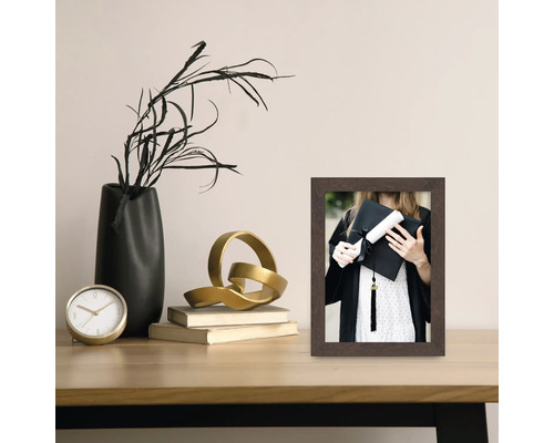 Decoratieve fotolijst op een tafel met klok, vaas en decoraties