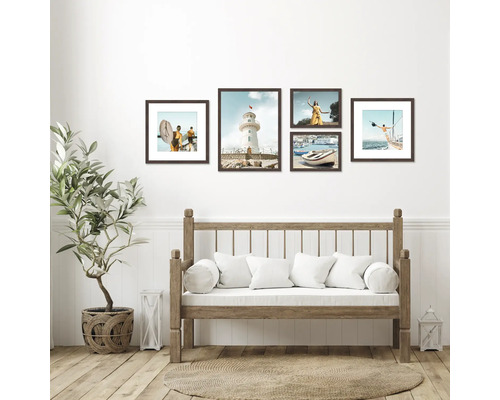 Wanddecoratie met een selectie ingelijste foto's boven een houten bank